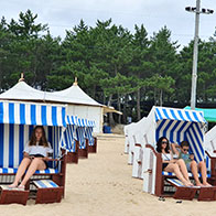 해변에 설치된 바스켓에서 사람들이 편하게 앉아 태양광을 즐기고 있는 모습